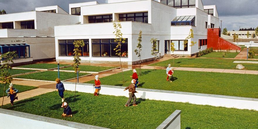 Lapsed mängivad modernistliku maja ees murul
