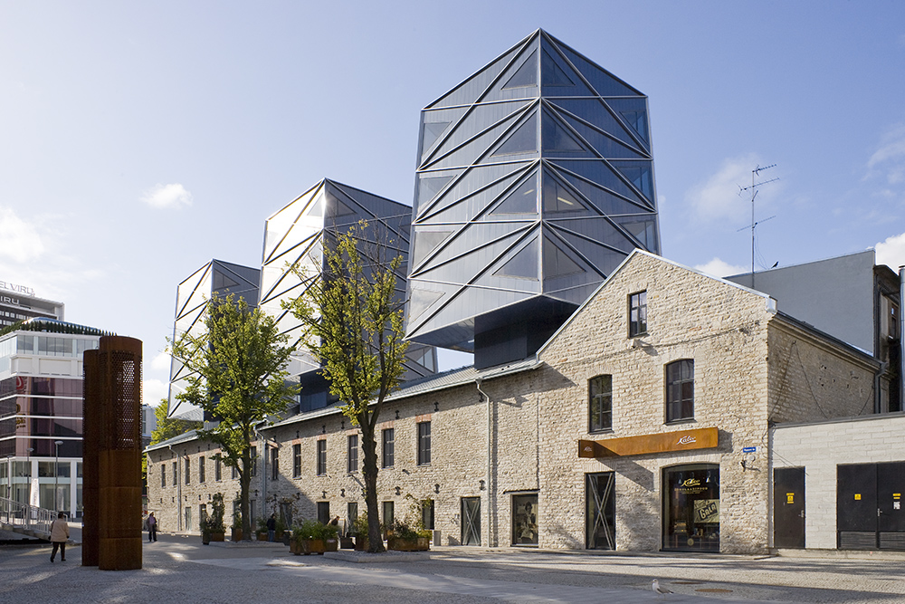 An old lime stone building topped with modern glass structures